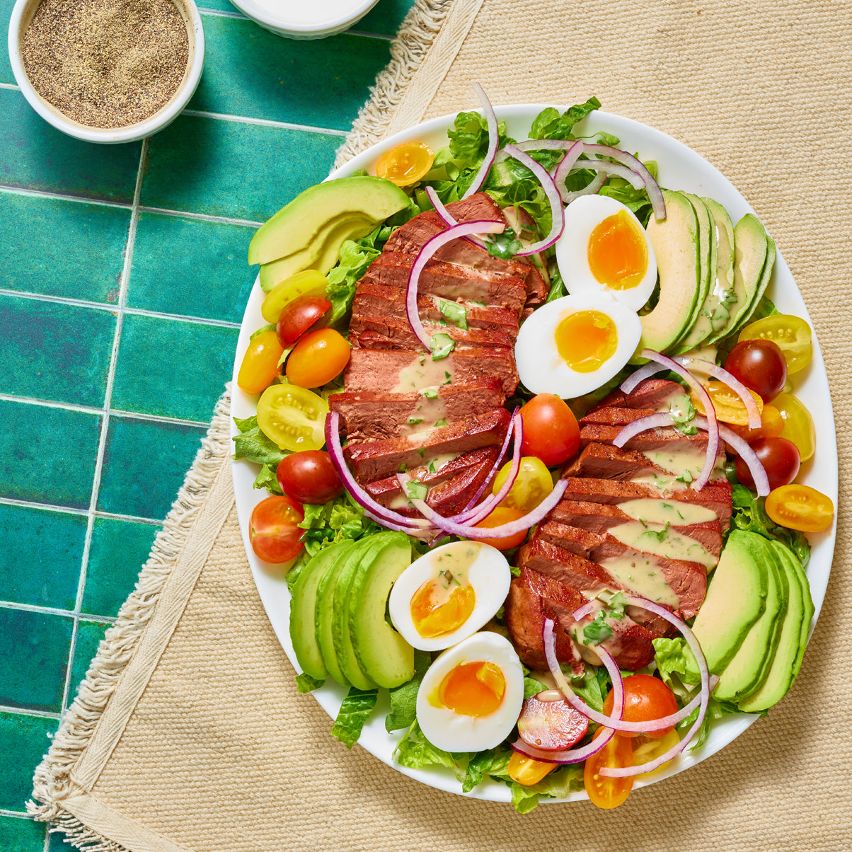 a platter of slices of meati classic steak with different vegetables and boiled eggs.